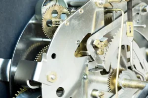 Fotografía de primer plano que muestra la compleja maquinaria interna de un reloj mecánico con ruedas dentadas, ejes y placas metálicas, relacionada con el estudio del tiempo y la trigonometría en relojes análogos