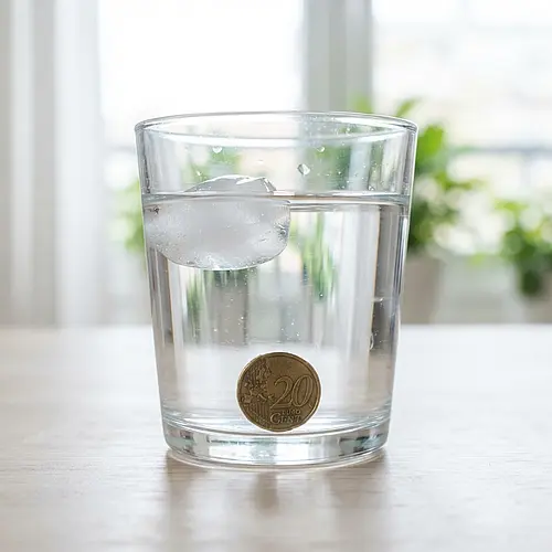 Hielo flotando y moneda hundida en un vaso de agua: ejemplo de qué es la materia y sus propiedades